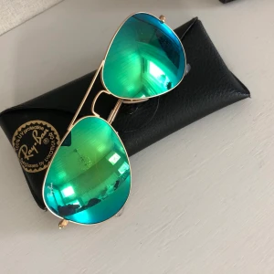 Solglasögon RayBan  - Äkta RayBan solglasögon med grönt spegelglas och guldig ram. Pilot-modell. Fint skick. Original glasögonfack medföljer. Köparen står för eventuell frakt.
