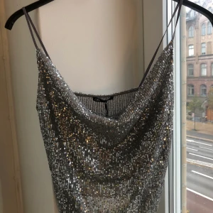 Glittrig topp - Snyggaste festtoppen !! Har silvriga paljetter med löst tyg på bysten. Aldrig använd & prislapp kvar.  Har massor av snygga toppar uppe på min profil - kombinera gärna fraktpriset genom att köpa andra plagg. 🤩