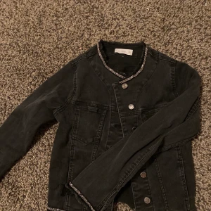 Jeans jacka  - Svart kort jeansjacka med strass längst kanterna. slutar vid höfterna. 