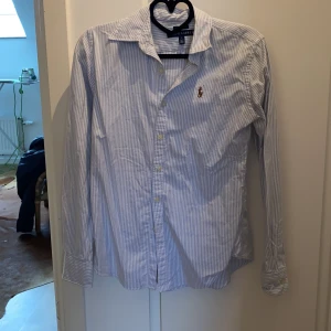 Ralph lauren skjorta  - Ljusblå / vit randig Ralph lauren skjorta, slim - fit. Storlek 2 (motsvarar x-small / small. Använd ett fåtal gånger, väldigt fint skick. 