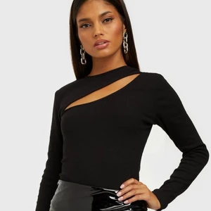 Ribbad topp från Nelly - Ribbad, stretchig långärmad svart topp med fin cutout detalj på framsidan!