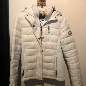  - Fin vit vinterjacka från Superdry. Avtagbar päls på luvan och dubbeldragkjedjad. Fint skick o nydlingen kemtvättad. Nypris 1295kr men säljer för 400kr eller bud med rätt att nekas