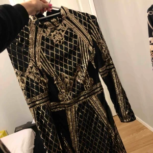  - Svart knälång klänning med guldiga paljetter, storlek 34. Aldrig använd, bara hängt på klädstången.  