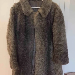  - Unik vintage silvrig kappa i fårull. Behöver lappas lite på axeln men skickar med extra fårskinn i samma material och färg. 
