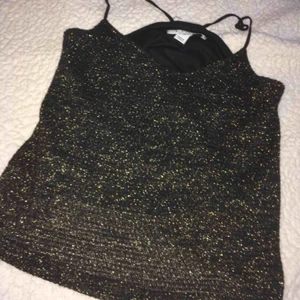  - En glittrig topp för vardags eller festligare tillfällen. Storlek Small. Använd 1 gång. Har knytit på axelbanden, men knutarna går att knyta upp. •Köparen står för frakt!