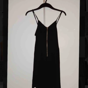  - Svart, kort klänning från H&M, tight passform upptill och lösare från midjan och neråt. Dragkedja i mitten och sparsamt använd. 