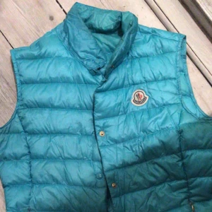  - Dunväst i rolig turkos färg. Sliten. 