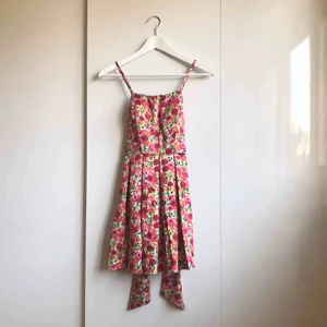 Blommig klänning  - Endast använd en gång, det var 2010 som andra bilden visar. Sedan dess har denna fina klänning med knytning bak endast hängt undangömd långt in i garderoben. Hoppas någon annan klär sig i den nu! Köpare betalar frakt.