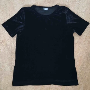  - Svart T-shirt från Cubus i 95% polyester och 5% elastan. Materialet känns som sammet. På båda sidorna är det en liten slits. Använd en gång.  Kan mötas upp alt. skicka.