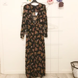  - Tunn, halvtransparent långklänning med slits fram och små knappar i ringningen. Lika fin att ha knäppt (bild 2) som uppknäppt (bild 1) med en spetstopp under t.ex! Klänningen är helt ny med lappar kvar.