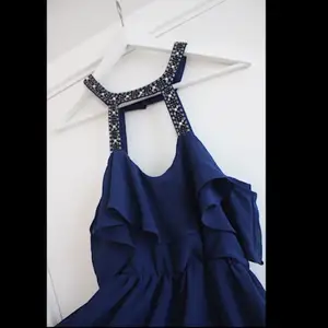 Snygg blå klänning med fina detaljer och öppen rygg. Aldrig använd! 