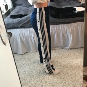 adidas originals adibreak TP - Marinblå och vita adidas originals adibreak typ byxor, knappar längstsidorna. Långa i benen och höga i midjan. Använda ca 3 gånger. nypris ca 700kr