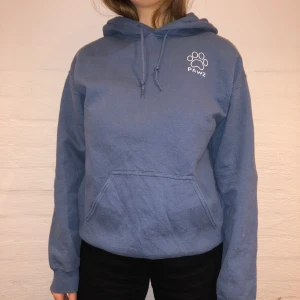 PAWZ Hoodie  - Vi säljer denna blå hoodie från märket PAWZ som är en sorts organisation för hundarnas rätt. Nypris 500kr och vi säljer för 279kr.  Den har ingen storlek men passar som en M. Personen på bilden är 165cm och brukar ha på sig M. Inga defekter på hoodien. Kontakta oss på Plick eller vår Instagram @wanderetro. Om flera visar intresse blir det budgivning. Köparen står för spårbar frakt på 66kr. 🤍 