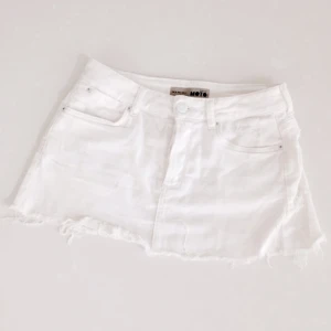  - Kortkort vit kjol från Topshop med slitna kanter. Knäppning med 4 knappar. Storlek S, W26. 
97 % bomull, 3 % elastan.