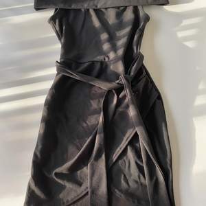 Tight stretchig svart klänning. Offshoulder med en band i midjan som framhäver midjan. Väldigt fin klänning. Säljs pågrund av att lite för liten för mig. Aldrig använd!! Bara testad