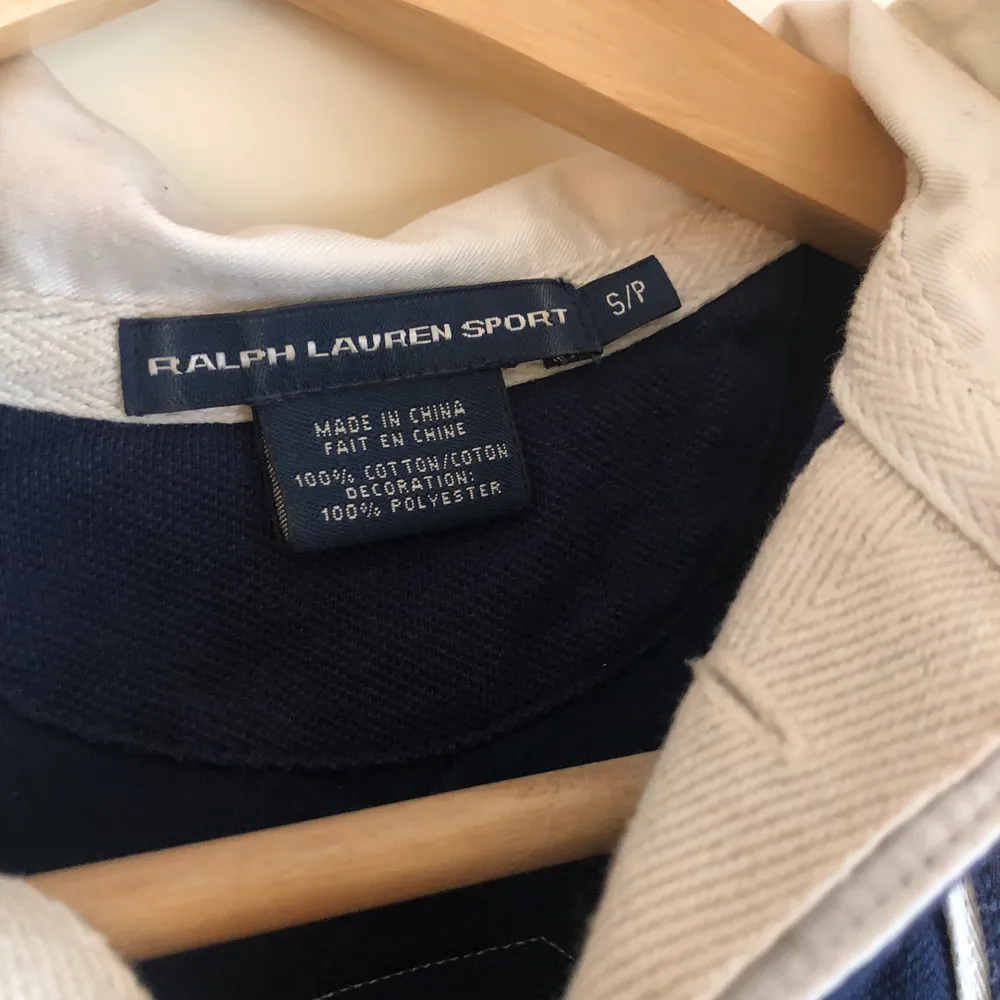 Marinblå tröja med vit krage och broderade märken på bröstet. Från Ralph Lauren. I nyskick, aldrig använd.. Tröjor & Koftor.