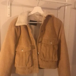 Bik bok, höst jacka. Användts fåtal gånger, i bra skick. Stl XS - Randig brungul jacka. Två fickor på vardera sida. Silvriga knappar. Vit filttyg på insidan. Från bik bok