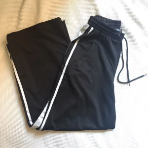  - svarta vida byxor i glansigt sportmaterial! supersköna men används inte av mig, därav i princip nyskick.