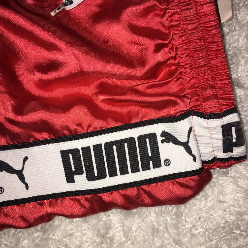 Sportiga Puma-shorts i glansigt material, väldigt gott skick, förutom att på ett av snörena har slutdubben fallit av, men själva byxan består intakt. Shorts.