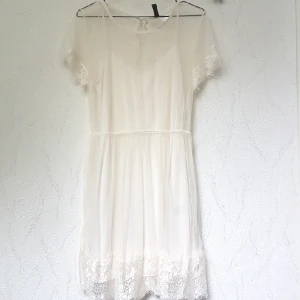  - Vit klänning i spets med en fastsydd underklänning. 