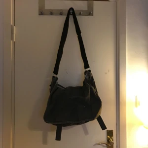  - En snygg väska med bra förvaringsmöjligheter. Den fungerar bra att använda till både jobbet och skola. Det finns fyra fickor, två i fram, en stor i bak och en liten inuti. Väskan är använd men i gott skick.    Frakt ingår INTE i priset 