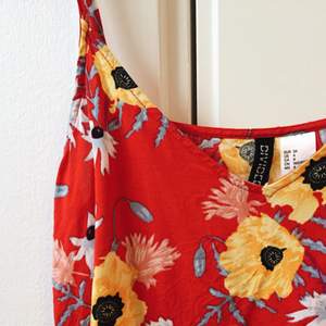 Oanvänt Rött linne med stora blommor från H&M. Justerbara band.