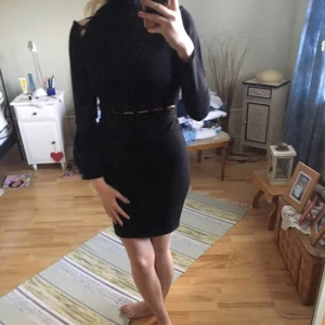  - Svart klänning med cutouts. Har dragkedja på sidan av nederdelen och längst nacken/ryggen på överdelen. Helt oanvänd