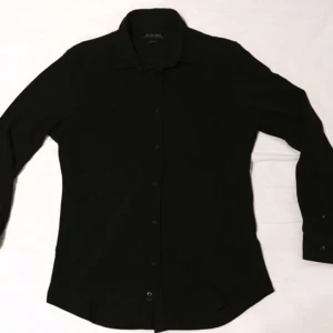  - Kolsvart skjorta i lite grövre tyg som sitter som ett smäck!  SLIMFIT Edsast använd 1 gång. 