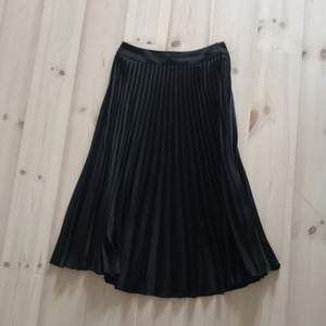 Plisserad vadlång kjol svart blank från Modern Classics h&m  Nypris 399:- Lite vid/rak i modellen, dold dragkedja i sidan  100% polyester  Passar 34 (XS)  Begagnad men i fint skick  