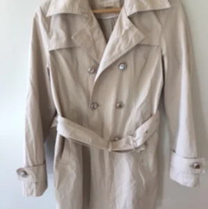 ”Trenchcoat Michael Kors” - Trenchcoat Michael Kors. Beige i storlek 34-36. Fint skick. Klassisk design med snygga detaljer som knappar med ingravering ”Michael Kors”. Kan hämtas i Jönköping eller så skickar jag den till dig och då står du för frakten. Om du vill köpa så hör av dig! 🙂 