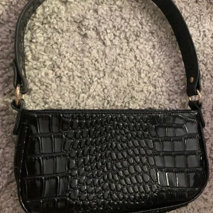 Axelremsväska  - Hej! Säljer nu min svarta axelremsväska med guld detaljer. 