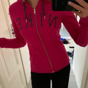 Rosa Nike hoodie - Rosa Nike hoodie från Nike med dragkedja. Säljer pga att den ej kommer ull användning. Fett snygg och lite tajtare i modellen. Storlek S men passar också en XS. Skitsygg. Minns ej vart den är köpt, Intersport?