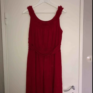  - Vacker röd klänning som går över knät. Har fina detaljer som är rosor på axelbanden 