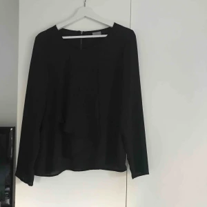  - En svart jättefin blus från Vero Moda. Fina detaljer, en dragkedja som går en liten bit på ryggen och volanger längst ner(kan skicka fler bilder vid intresse) använd 1 gång. 