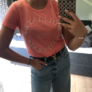T-shirt med text - Korall-rosa t-shirt med texten ”HOLLISTER CALIFORNIA”, FRAKT INGÅR I PRISET, kontakta för fler bilder eller frågor, buda gärna