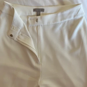 Vita kostymbyxor med slits - Säljer mina vita kostymbyxor med slits från HM då jag tycker att dem sitter alldeles för tajt. Byxorna har bara använts två gånger och är i jättefint skick förutom längst ner på ena byxbenet där jag fått en liten fläck som inte gått bort (se sista bilden).