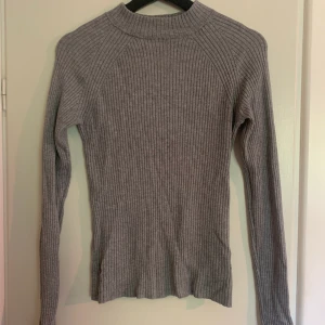 Grå tröja från Gina Tricot - En superskön stretchig tröja från Gina Tricot. Lite högre i halsen. Måttligt använd så i fint skick. Storlek M men skulle lika gärna passa en S. Frakt tillkommer💋