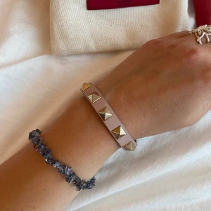 Valentinoarmband - Armband från valentino köpt på Selfridge. Rosa med guldnitar, dammodellen! Allt på bilden ingår. Har tyvärr blivit färgad lite vid hålen av en bläckpenna, syns nästan inte alls då den sitter på!