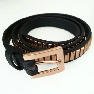 Svårt guld skärp Lindex S/M - Färg: svart/guld. Strl: S/M.   Mått: Total längd: 100 cm 1a hål - 84 cm 2a hål - 86 cm 3e hål - 89 cm 4e hål - 91 cm  Helt nytt fint skärp från Lindex. Med gulddetaljer av nitar.