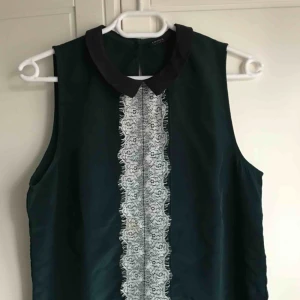  - Grön topp med svart krage och spetsdetaljer framtill. Finns en fläck på framsidan (se sista bilden) men det är inget som man märker jättemycket.   Köparen står för frakt ;)