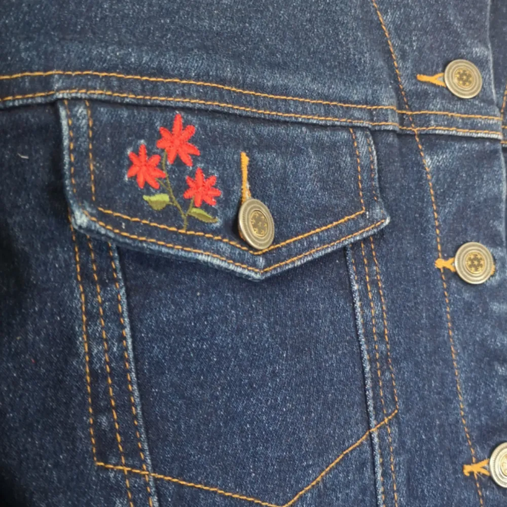 Mörkblå skitsnygg Jeansjacka med röda broderade blommor på ena bröstfickan. . Jackor.