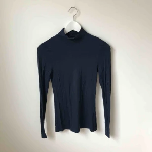  - Marinblå, tight polotröja. Använd ett fåtal gånger. Köparen står för fraktkostnad enligt postens portotabell.