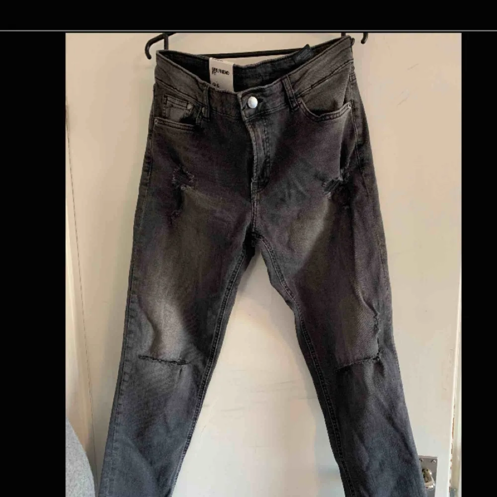 Svarta/gråa jeans med hål i båda knäna. Slitningar lite här och var. Aldrig använda, lapp kvar.. Jeans & Byxor.