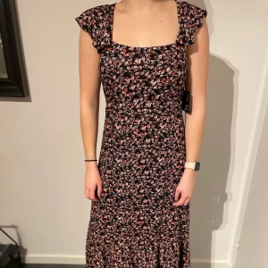 Blommig långklänning - En lång klänning med öppen rygg. Helt oanvänd och i storlek S. ☺️