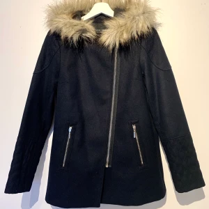 Helt ny vinterkappa/ st 36/ New Look/ mörkblå - Ny kappa i mörkblå, nästan svart med päls som ser äkta ut. Två fickor fram med dragkedjor i silver. Från New Look i storlek 10, motsvarar storlek 36. Materialet är i ull och polyester. Säljes då den tyvärr är för liten för mig. Jackan är aldrig använd.