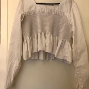 NAKD topp i stl 38 - Gullig sommartopp från NAKD. Tröjan är kortare i modellen och armarna är lite puffiga med knapp längst ner. Tröjan är använd fåtal gånger och utan slitningar. Pris går att förhandla. Stl 38