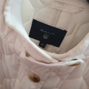  - Helt ny GANT jacka.  Inköpt på best of brands våren 2018 för 1 500 sek.   Vit med guldiga detaljer och vadderad.   Kan nötas upp i Huddinge, Älvsjö, Årsta, Globen & Västberga 