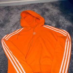 Snygg orange hoodie från adidas, lite kortare i modellen, använd ca 2ggr så jätte fint skick 