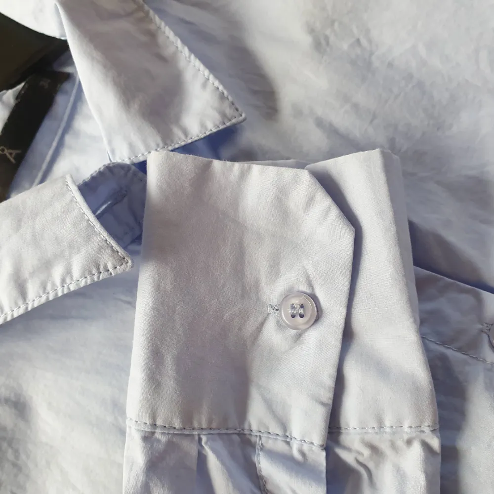 Ljusblå skjorta från Åhléns helt oanvänd.  Skjortan är i formen slim vilket betyder att den är insydd.   Kan mötas upp i Huddinge, Älvsjö, Årsta, Globen & Västberga. Skjortor.