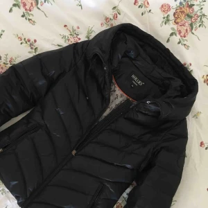  - Populär HOLLIES jacka med stor luva och hål för eventuell pälskrage. Strl 34, välanvänd men dugligt skick. Frakt tillkommer.